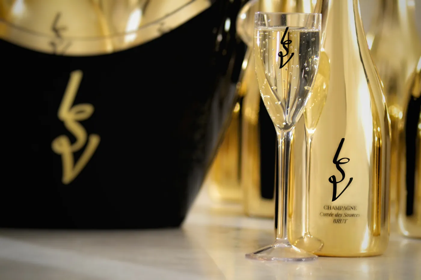 Seau à champagne noir au monogramme LSV avec une coupe et une bouteille dorées